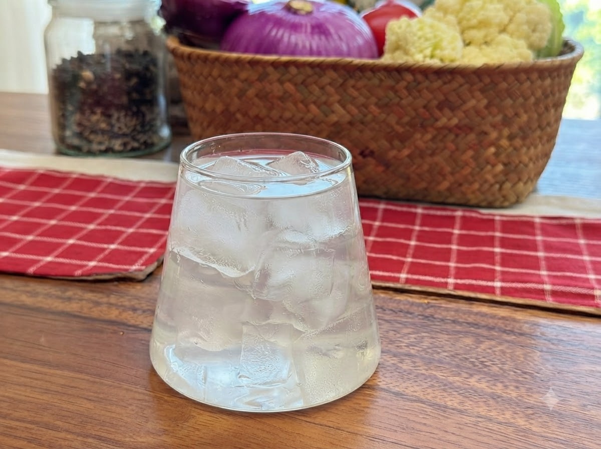 Agua de coco siendo vertida en un vaso transparente lleno de cubitos de hielo.