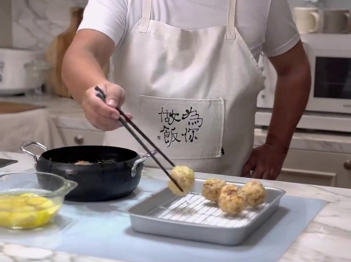 Albóndigas siendo retiradas del aceite caliente con unos palillos y puestas sobre una rejilla escurridora.