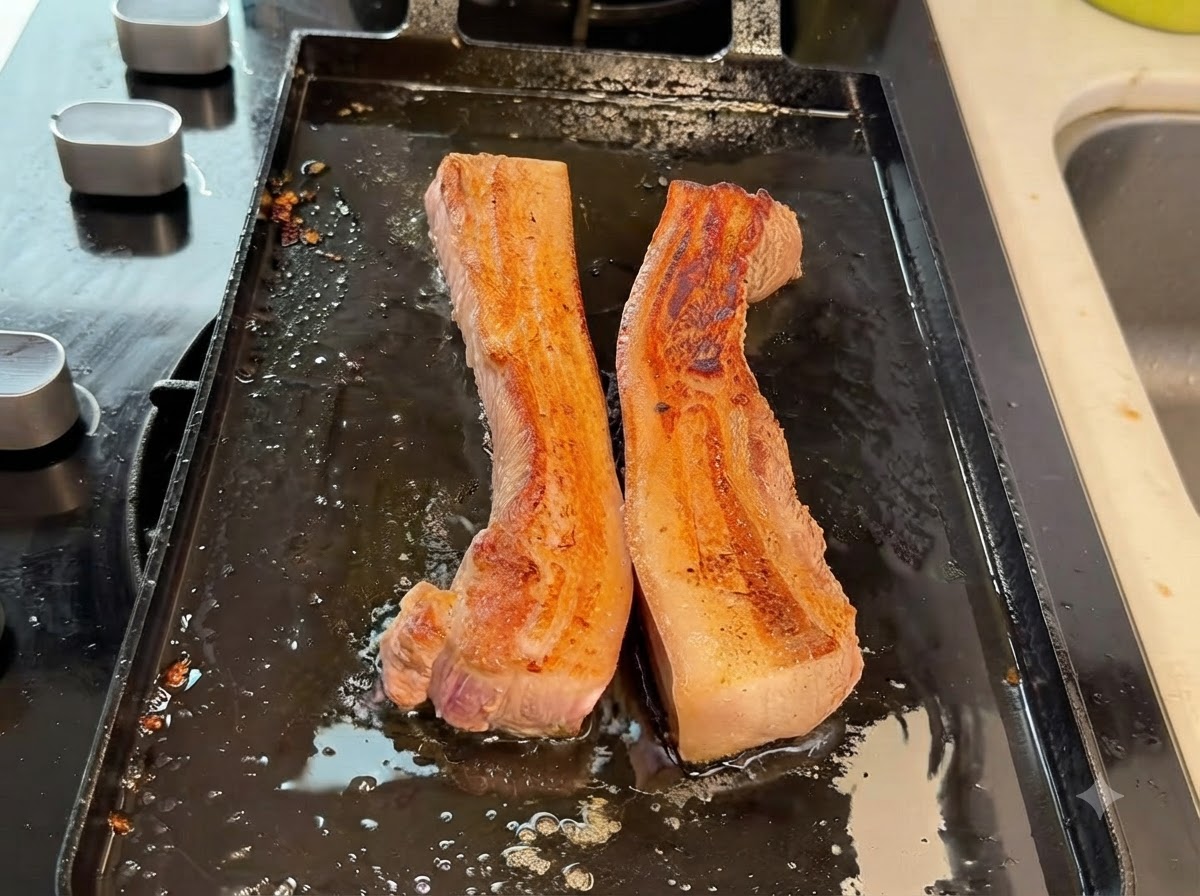 Tiras gruesas de panceta cortándose en trozos más pequeños con tijeras de cocina sobre la sartén.