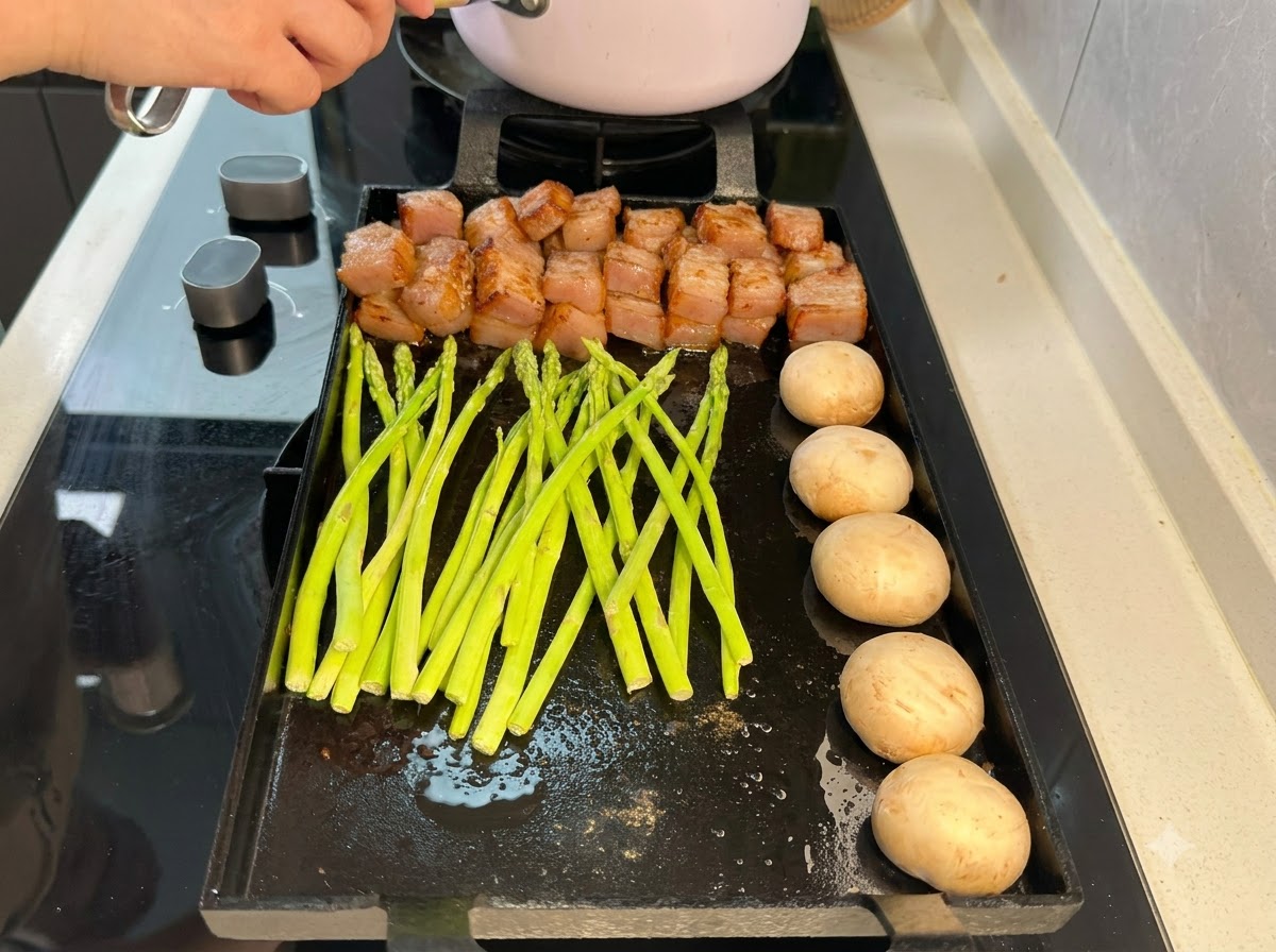 Brotes de espárragos verdes frescos dispuestos en la sartén grill junto al cerdo y los champiñones.
