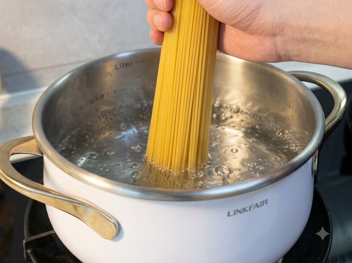 Una mano sosteniendo fideos de arroz secos mientras se sumergen en una olla de agua hirviendo.