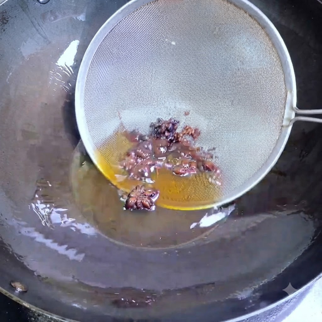 Un colador de alambre sacando anís estrellado y granos de pimienta de Sichuan del aceite caliente en un wok.