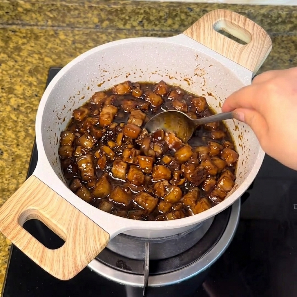 Azúcar blanco mezclado con una cuchara en la salsa de carne oscura a fuego lento.