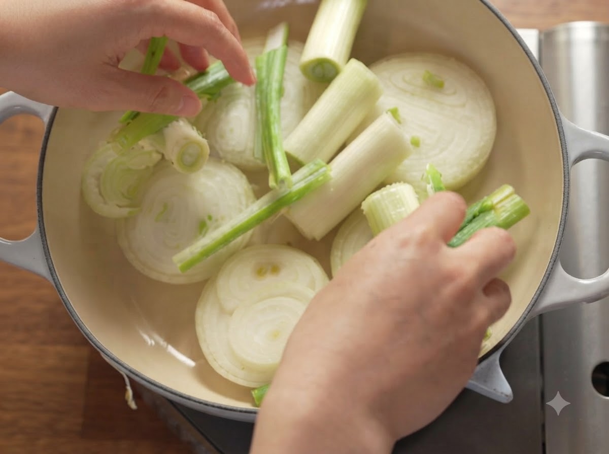 Rodajas de cebollas, cebollas verdes y manzanas dispuestas ordenadamente dentro de una olla holandesa pesada.