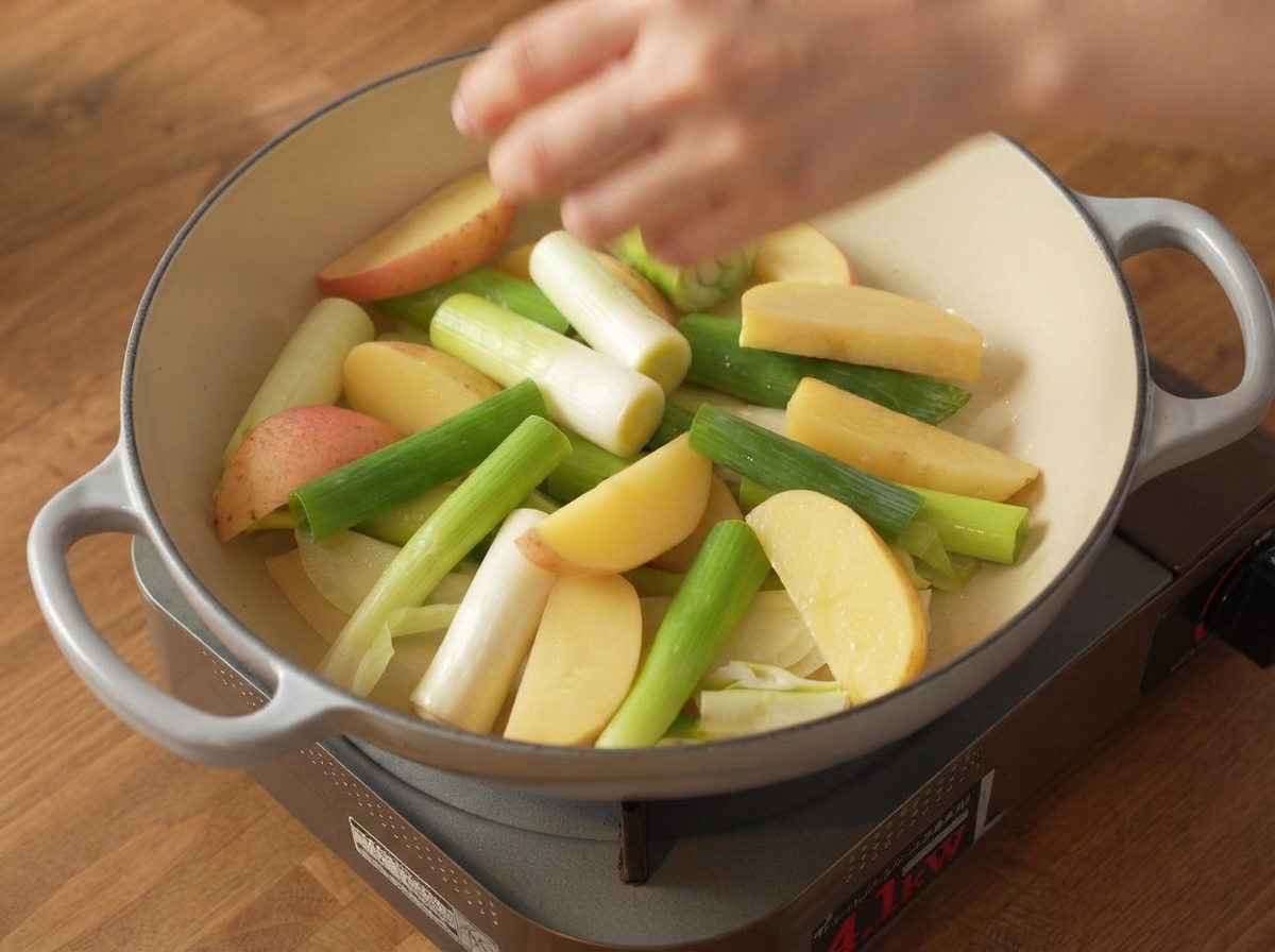 Tiras de panceta de cerdo crudas y sazonadas colocadas de forma segura sobre la capa de vegetales dentro de la olla de cocción.