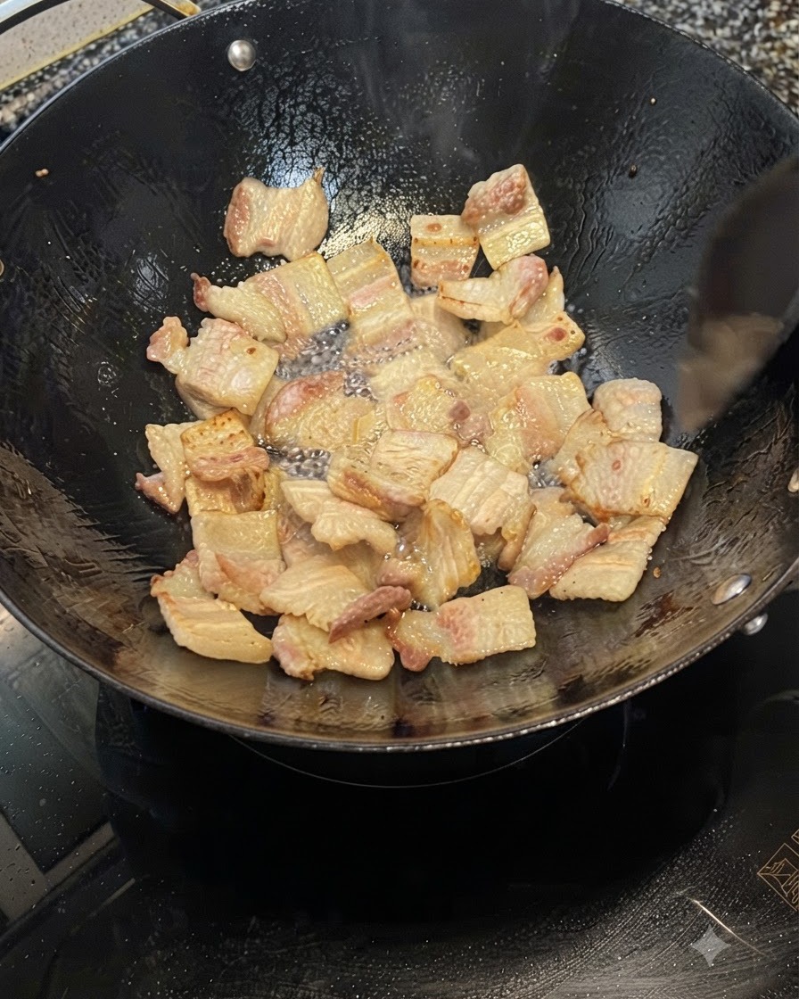 Rodajas de panza de cerdo friéndose en un wok, liberando grasa y volviéndose de color marrón dorado.