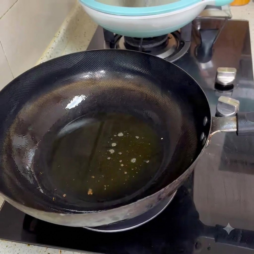 Dos cucharadas de pasta de frijol picante friéndose en aceite caliente dentro de un wok negro.
