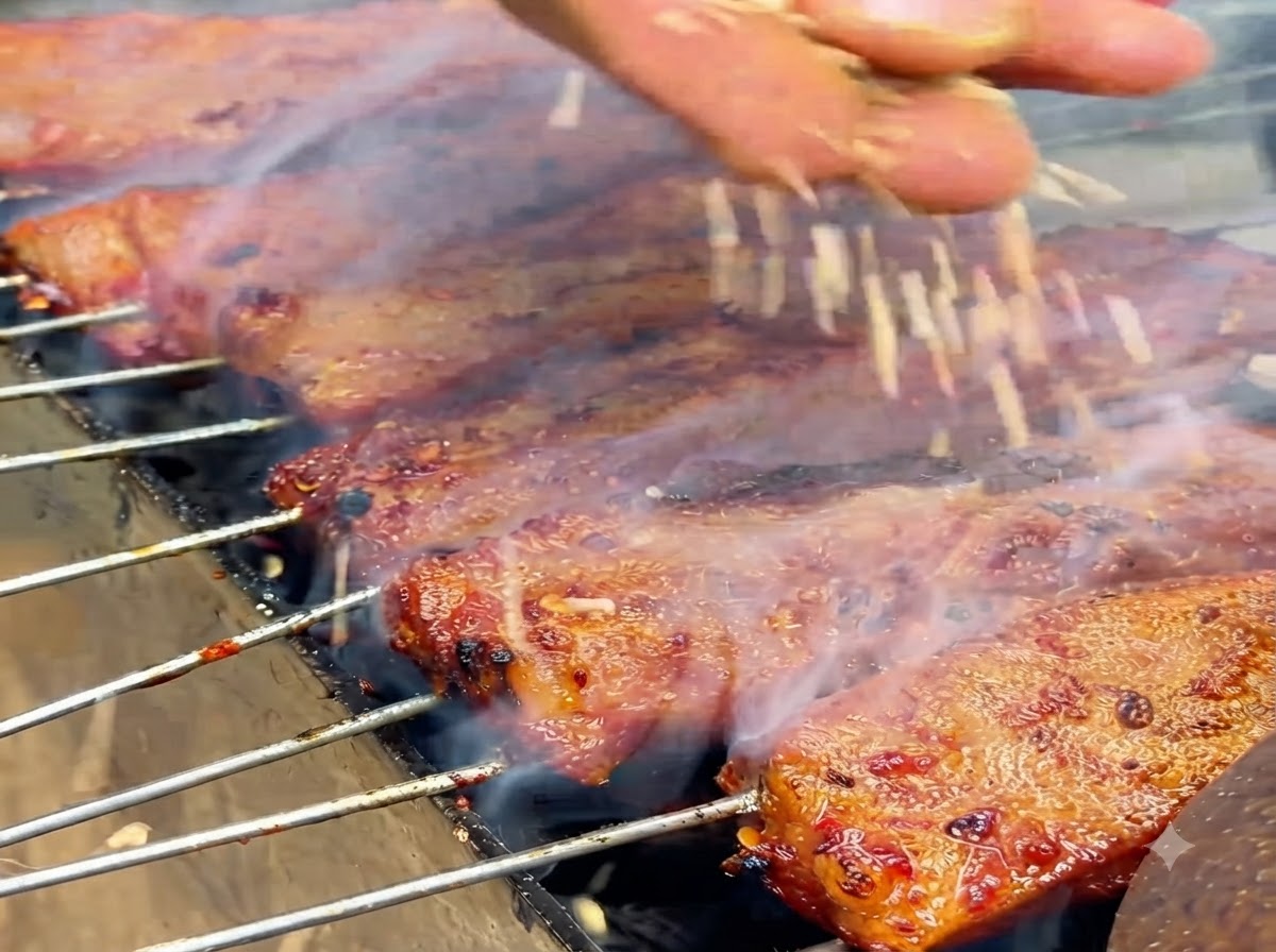 Semillas de sésamo blanco cayendo sobre costillas cocidas relucientes en una parrilla.
