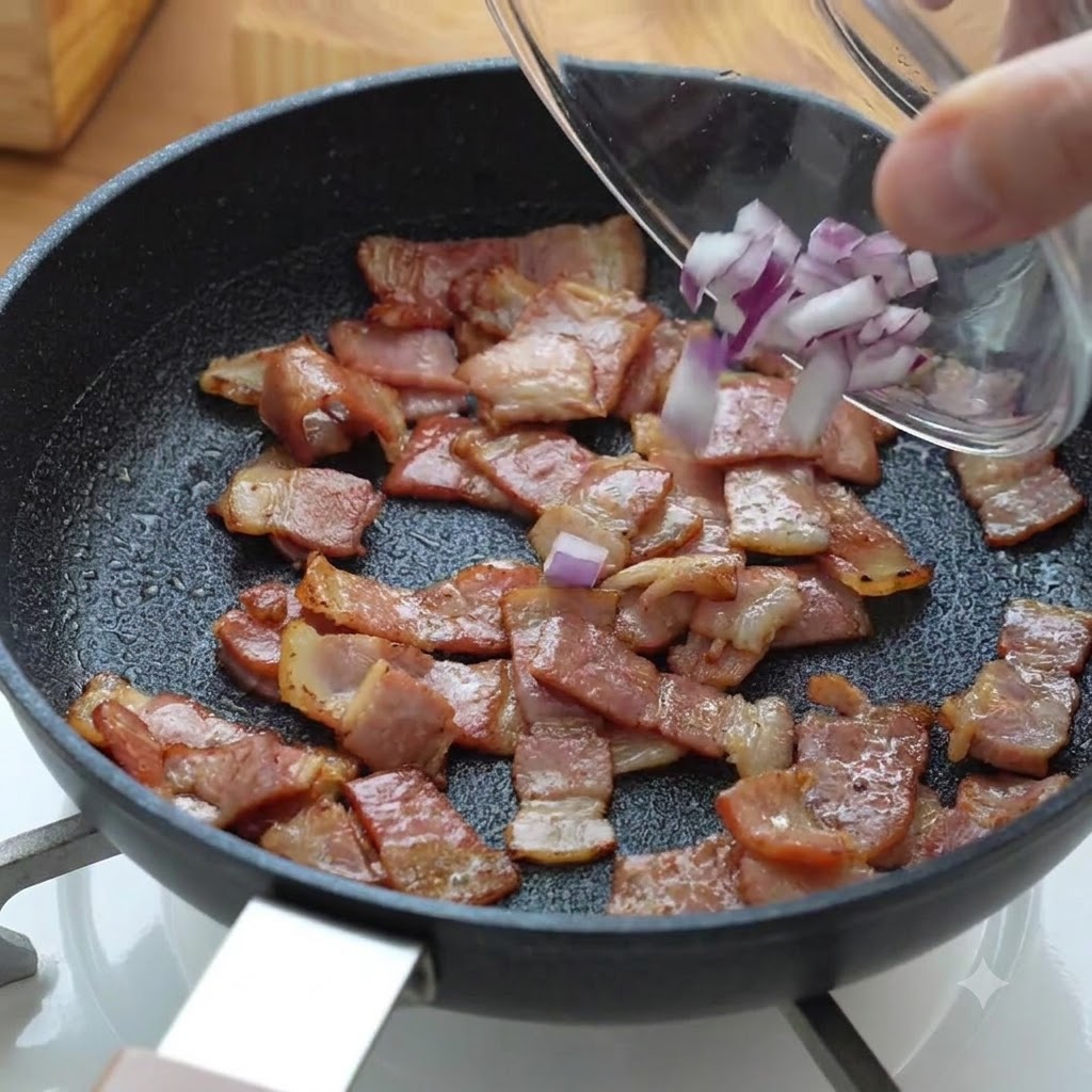 Trocitos de cebolla morada picada vertidos en la sartén con el tocino en cocción.
