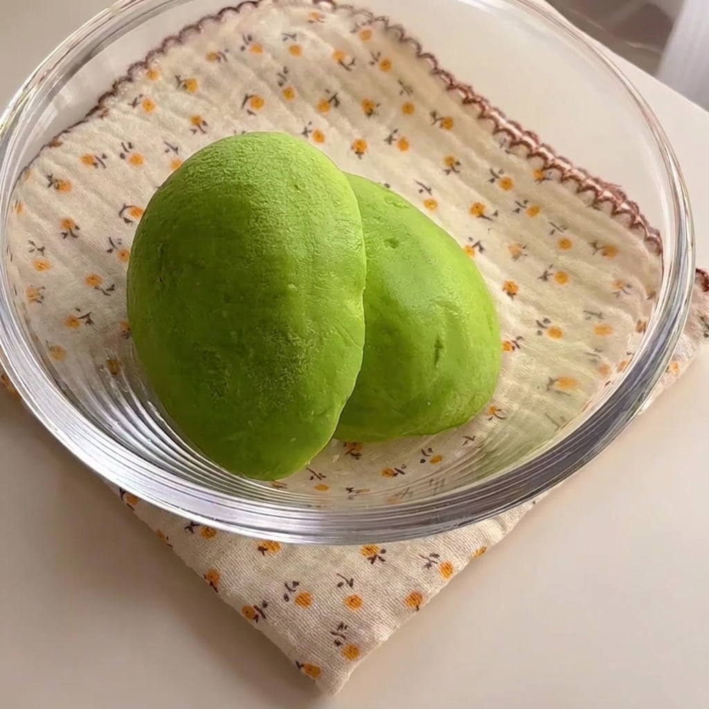 Dos mitades de aguacate verde vibrante sentadas dentro de un bol de vidrio.