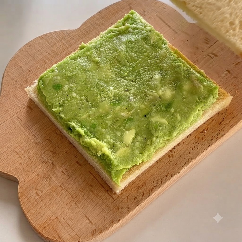 Una segunda rebanada de pan blanco colocada directamente encima de la capa de pasta de aguacate.