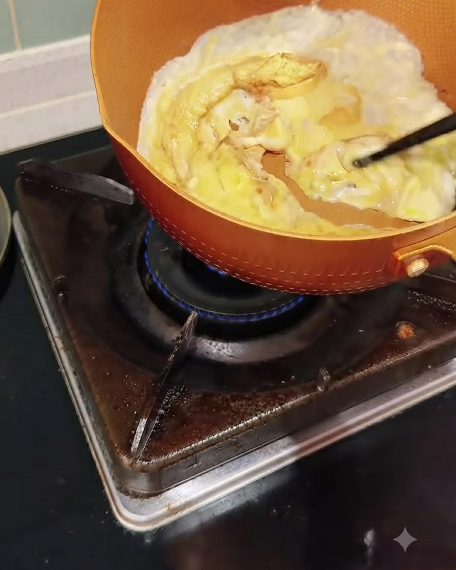 Huevos cocinándose en una sartén siendo empujados suavemente y revueltos con palillos.