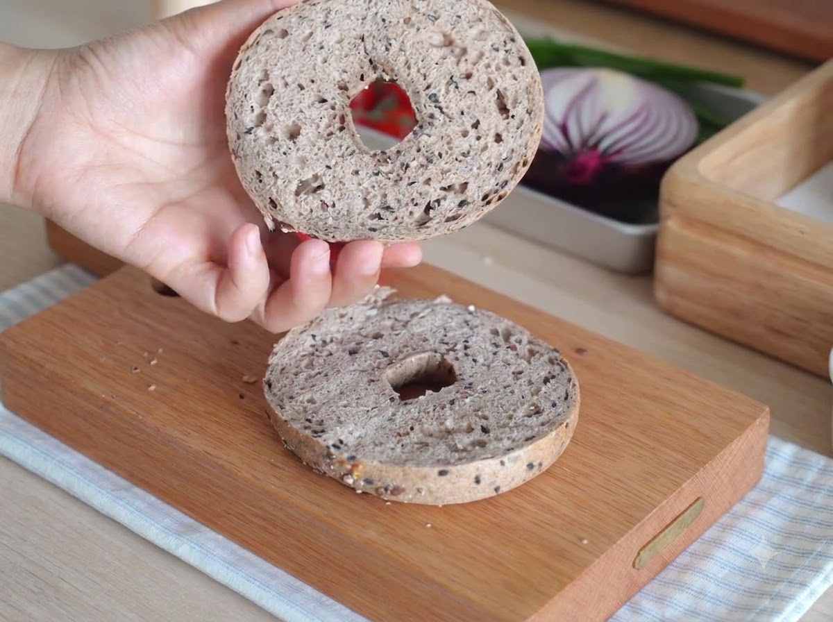 Dos mitades de bagel dentro de un pequeño horno de encimera blanco durante el horneado.