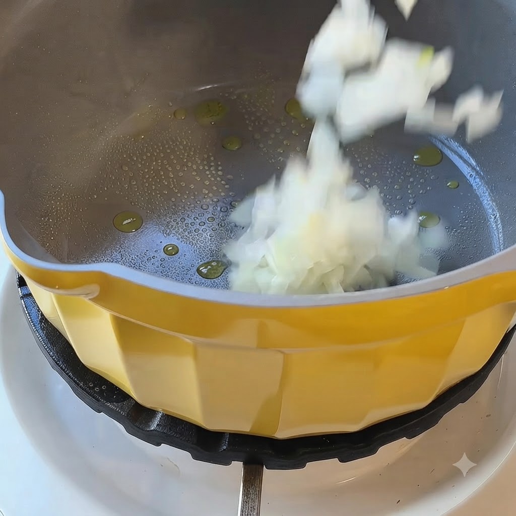 Cebollas blancas picadas cayendo en una olla amarilla con aceite caliente en una hornalla de la estufa.