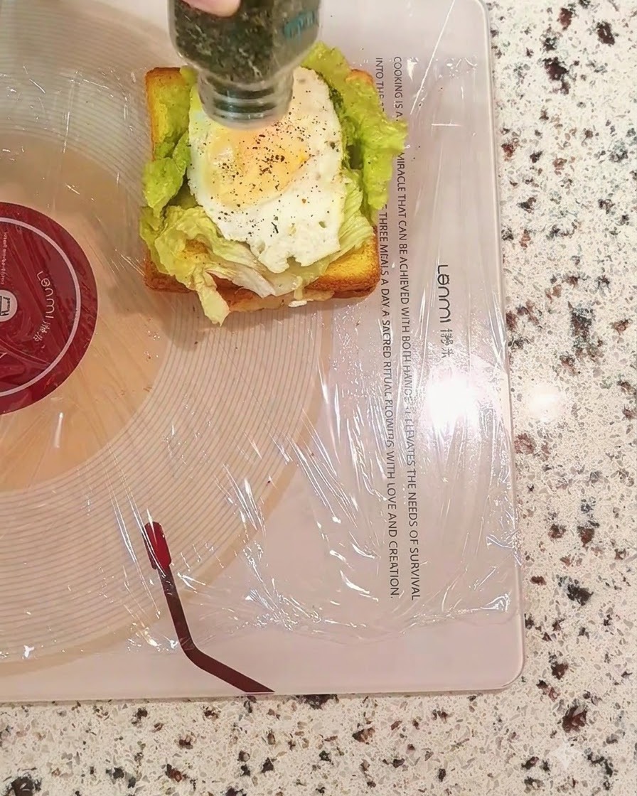 Espolvoreando perejil seco de un frasco sobre la capa de huevo del sándwich.
