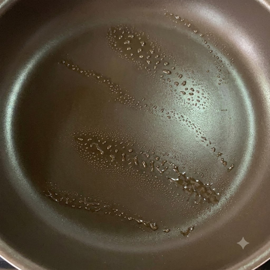 Una sartén antiadherente con un ligero spray de aceite preparada para sellar los muslos de pollo.