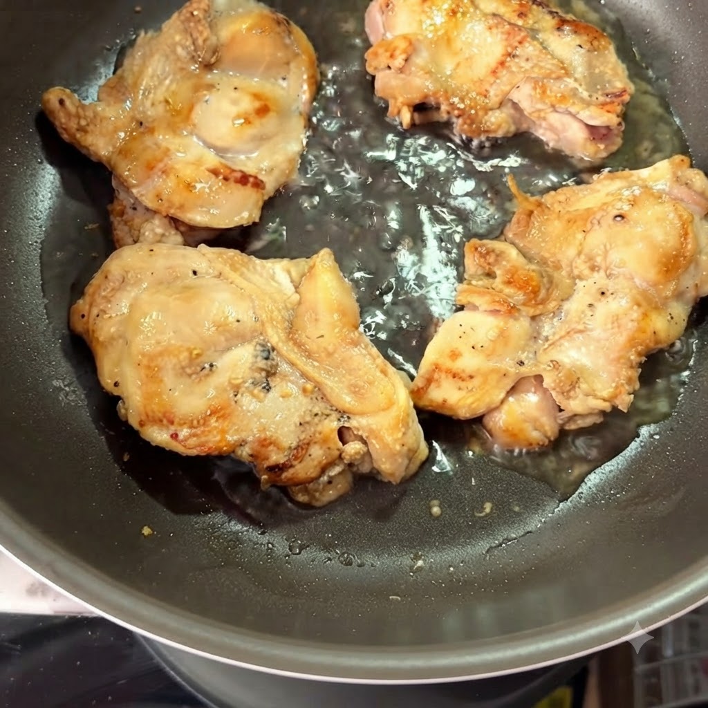Agua caliente siendo vertida en una sartén alrededor de los muslos de pollo sellados.