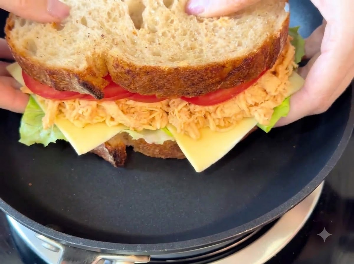El sándwich completo cocinándose en una sartén negra a fuego lento.