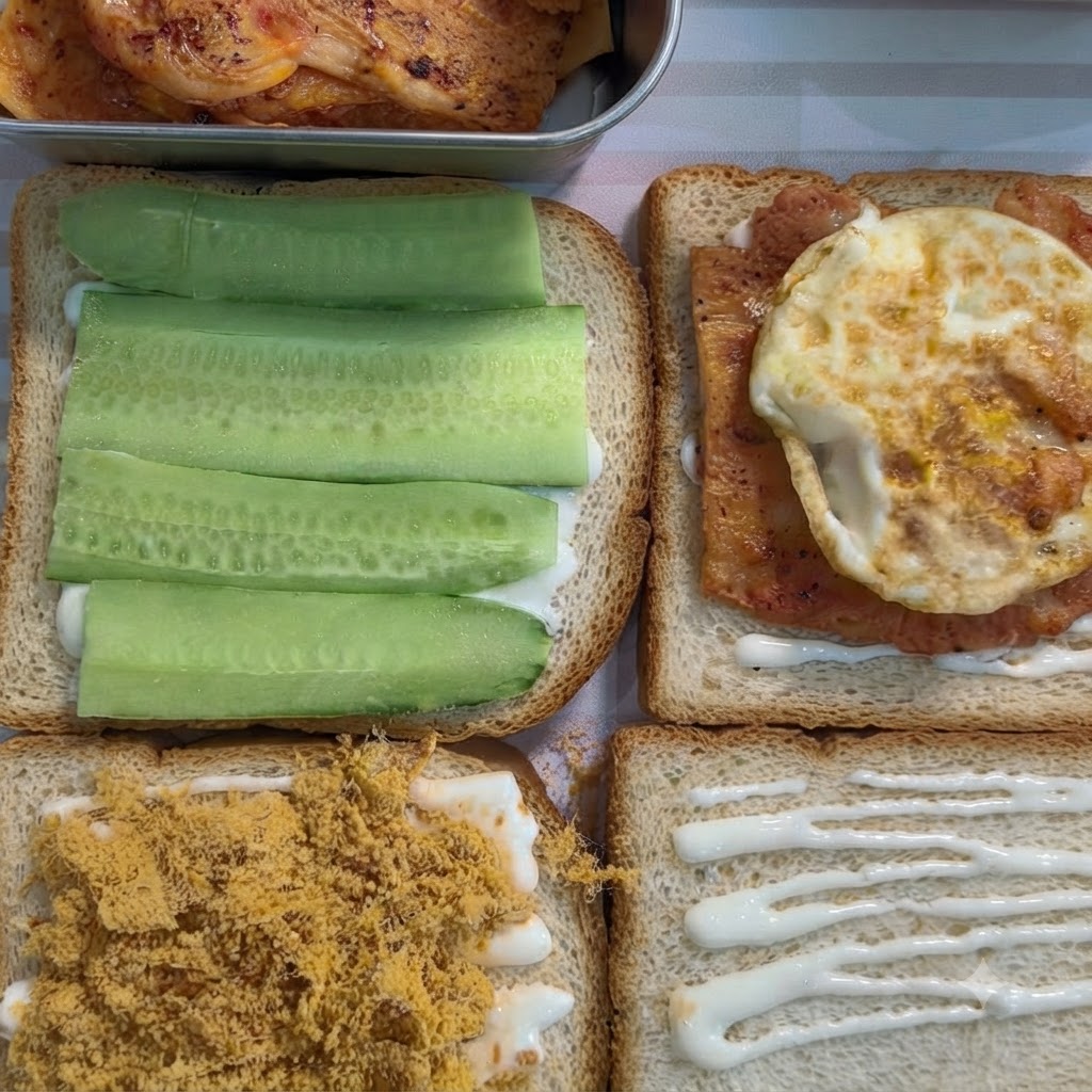 Una rebanada de pan de molde con crema blanca coronada con un trozo cocido de pollo sazonado y un huevo frito.
