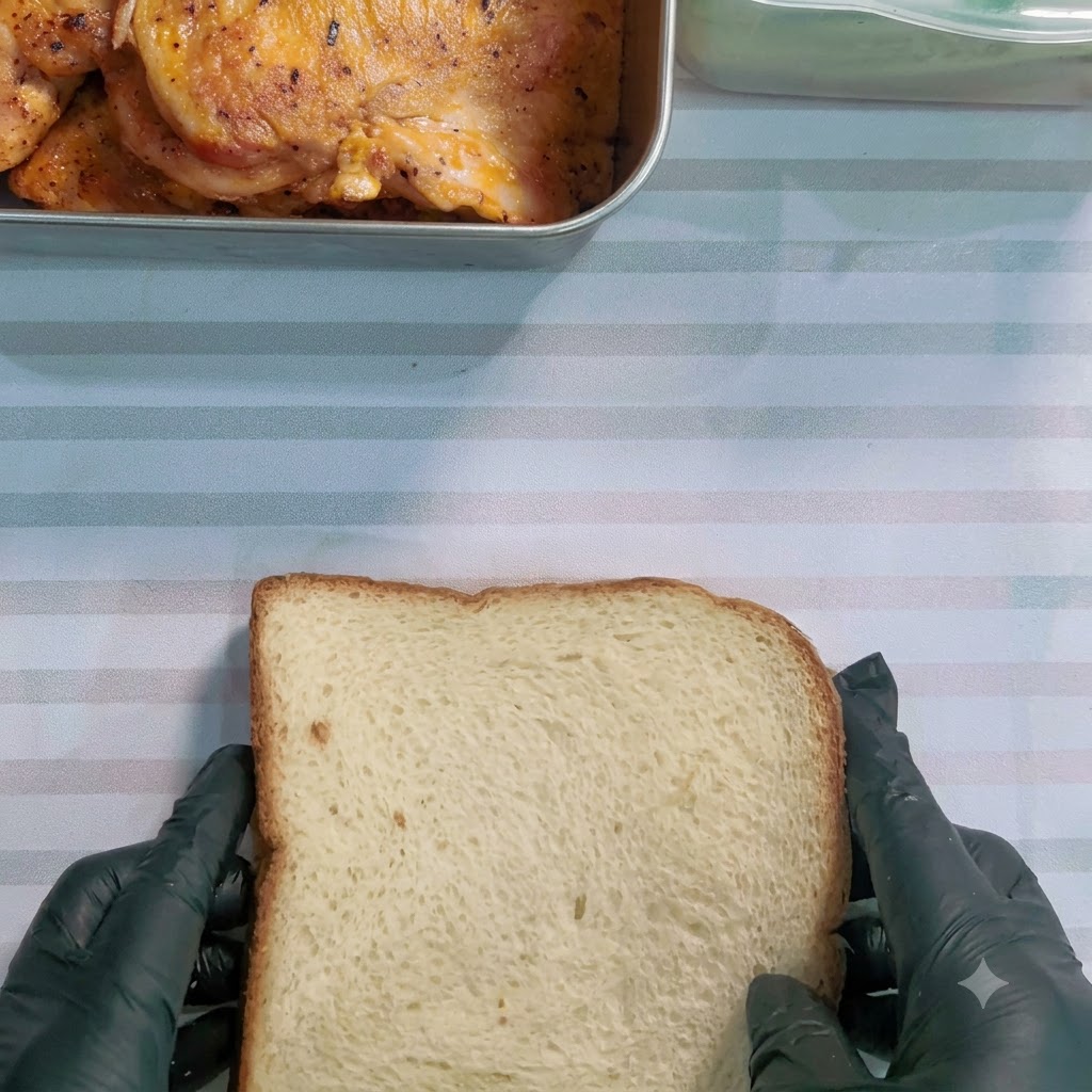 Un cuchillo de sierra cortando un sándwich envuelto en diagonal sobre una superficie a rayas.
