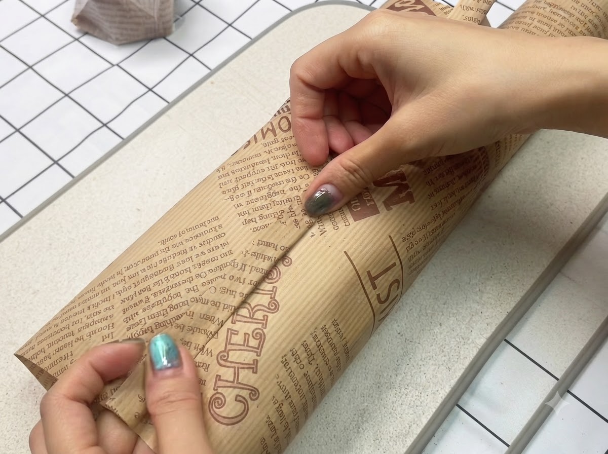 Un sándwich recién hecho envuelto de manera firme y segura en papel encerado marrón decorativo.