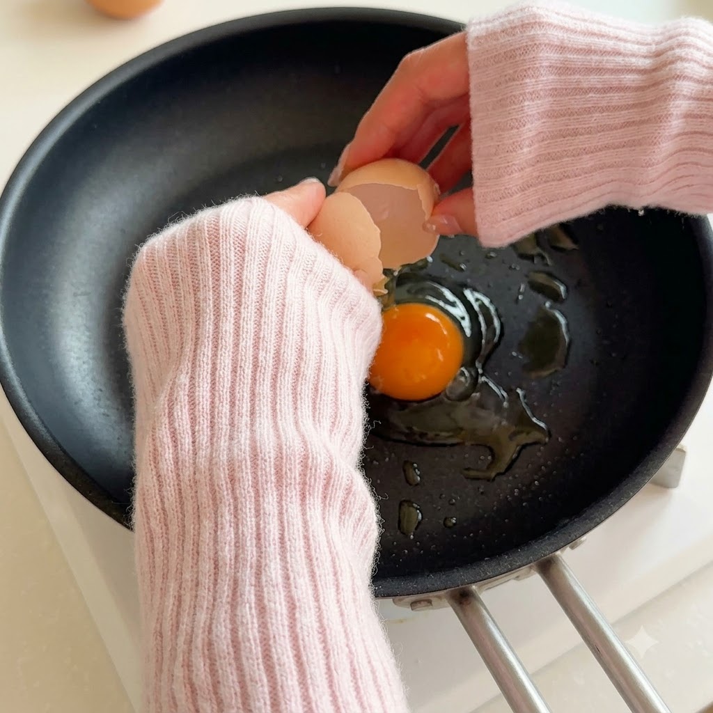 Un huevo rompiéndose en una sartén caliente con aceite.