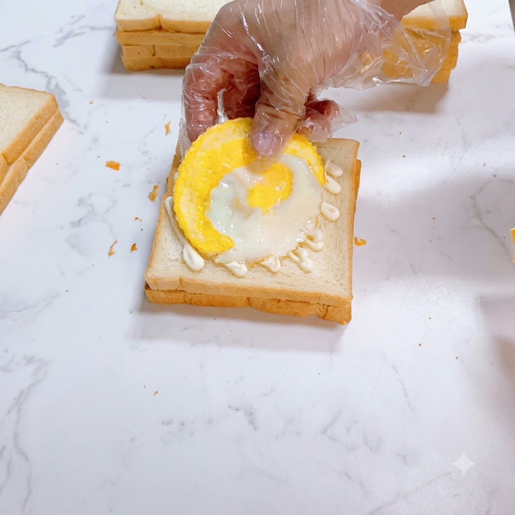 Un huevo frito colocado cuidadosamente sobre pan blanco untado con mayonesa.