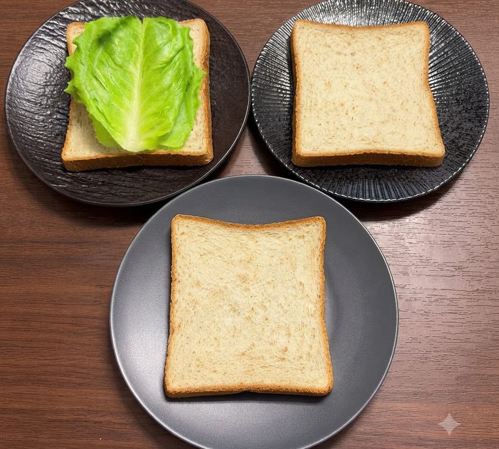 Hojas de lechuga verde fresca dispuestas ordenadamente sobre rebanadas de pan integral colocadas en platos negros.