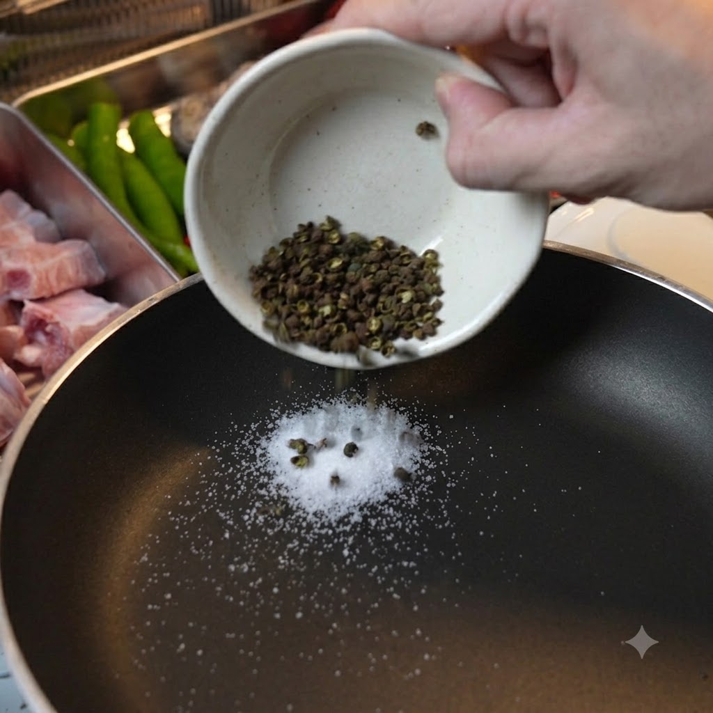 Granos de pimienta verde de Sichuan y sal gruesa vertidos en una sartén negra para el tueste en seco.