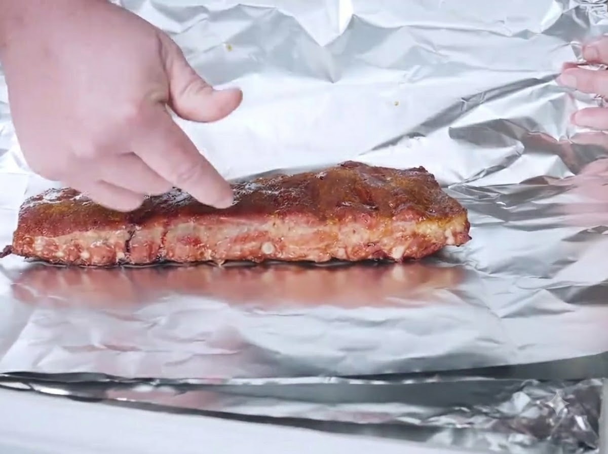 Costillas ahumadas colocadas en una hoja de papel de aluminio listas para ser envueltas.
