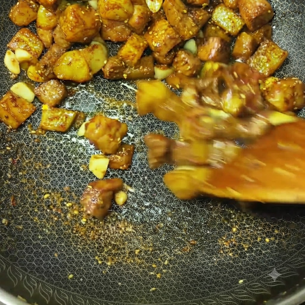 Cubos de carne y trozos de patata siendo salteados rápidamente en un wok con especias y condimentos visibles.