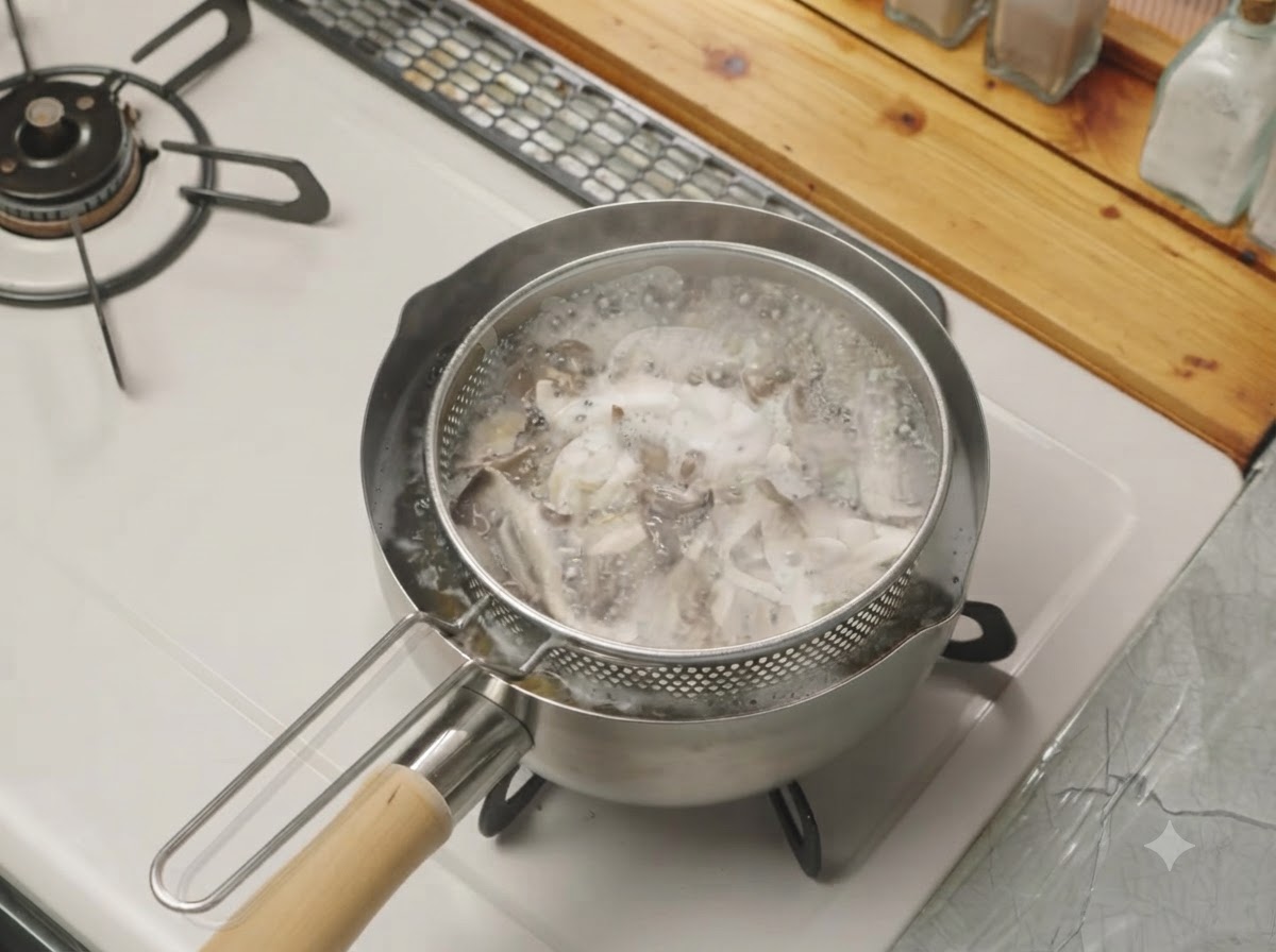 Setas desmenuzadas hirviendo dentro de un colador de malla colocado dentro de una olla con agua en la estufa.