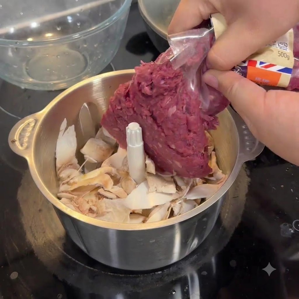Manos exprimiendo carne cruda de un paquete de plástico en el bol de acero de un procesador de alimentos lleno de trozos de champiñón.