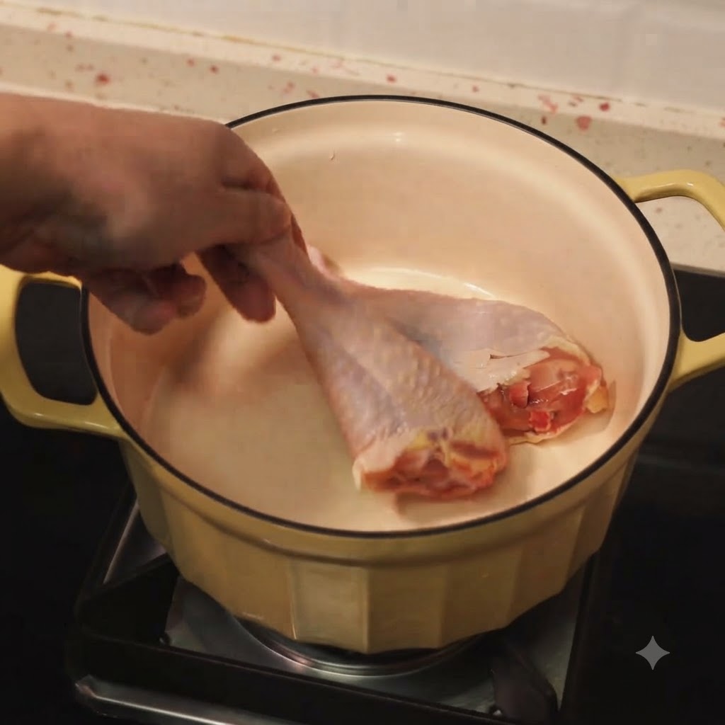 Muslos de pollo dorándose en una olla con aceite caliente.