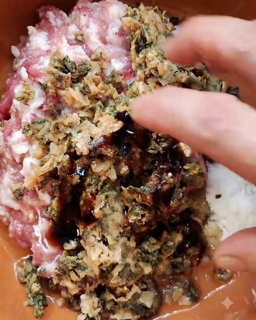 Una mano combinando cerdo picado, mostaza en hoja encurtida picada y condimentos en un bol marrón.