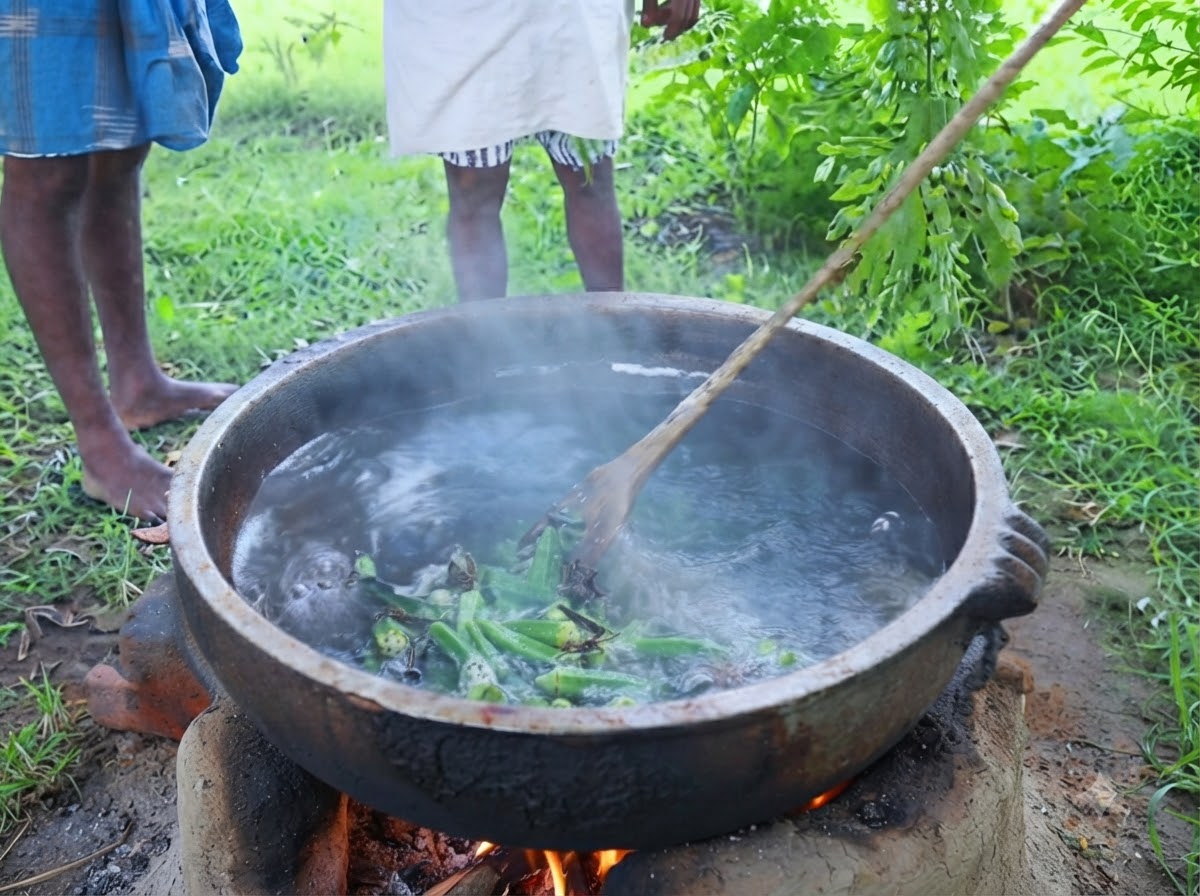 Hojas de curry verde frescas siendo desprendidas directamente de una rama hacia una olla humeante de aceite sazonado al aire libre.