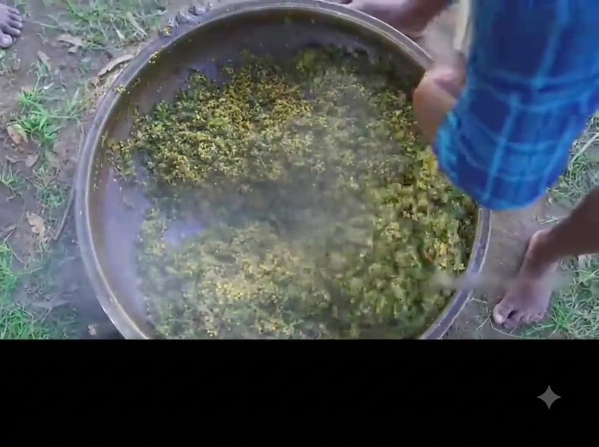 Una persona revolviendo el curry terminado de okra verde y huevo en una olla de hierro grande.