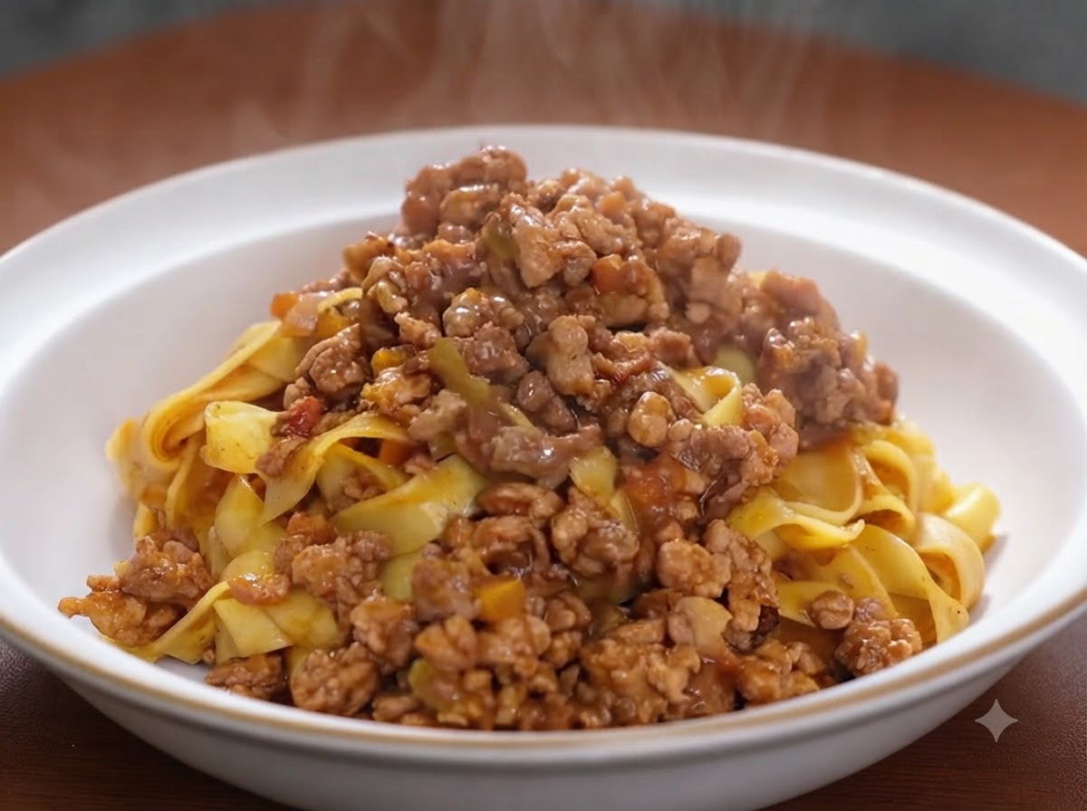 Pasta de tomate siendo integrada en una mezcla de carne dorada y verduras en una sartén.