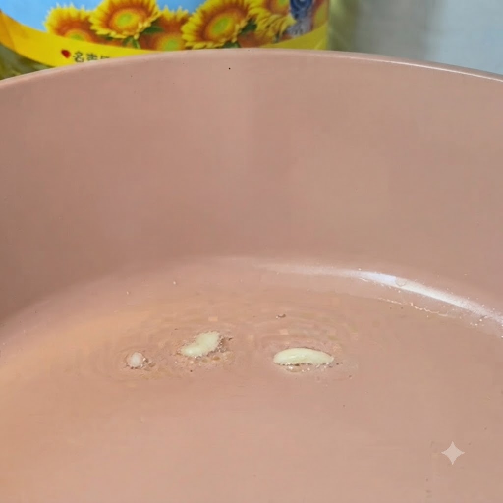 Ajo picado friéndose en una sartén rosa caliente con aceite.