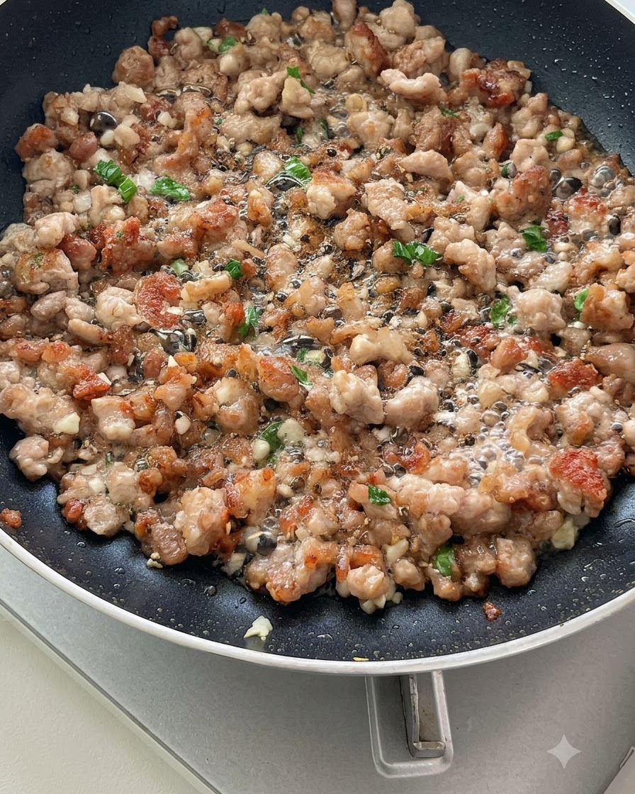 Tomates en rodajas salteándose con carne picada y aromáticos en una sartén, comenzando a soltar sus jugos.