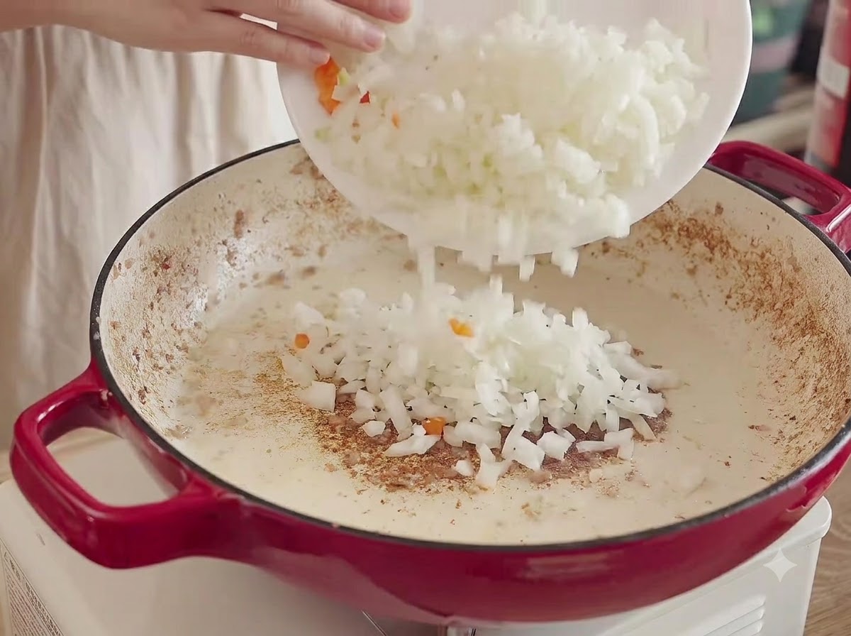 Cebollas, zanahorias y apio picados vertidos desde un plato blanco a la olla caliente para sofreír.