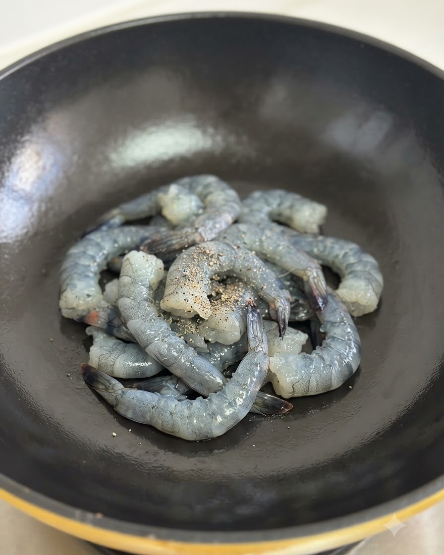 Camarones crudos sazonados con pimienta negra friéndose en un wok negro.