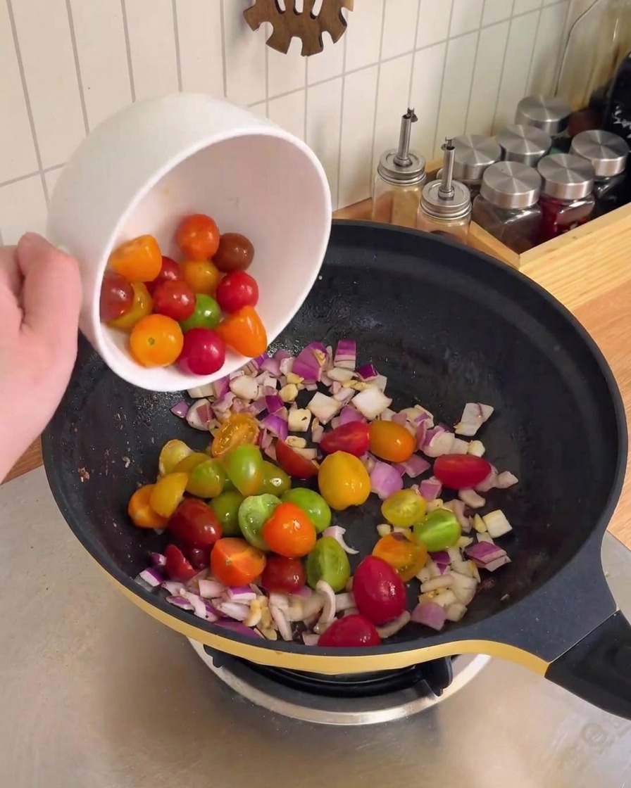 Cebolla morada picada y ajo siendo revueltos y salteados en un wok negro.