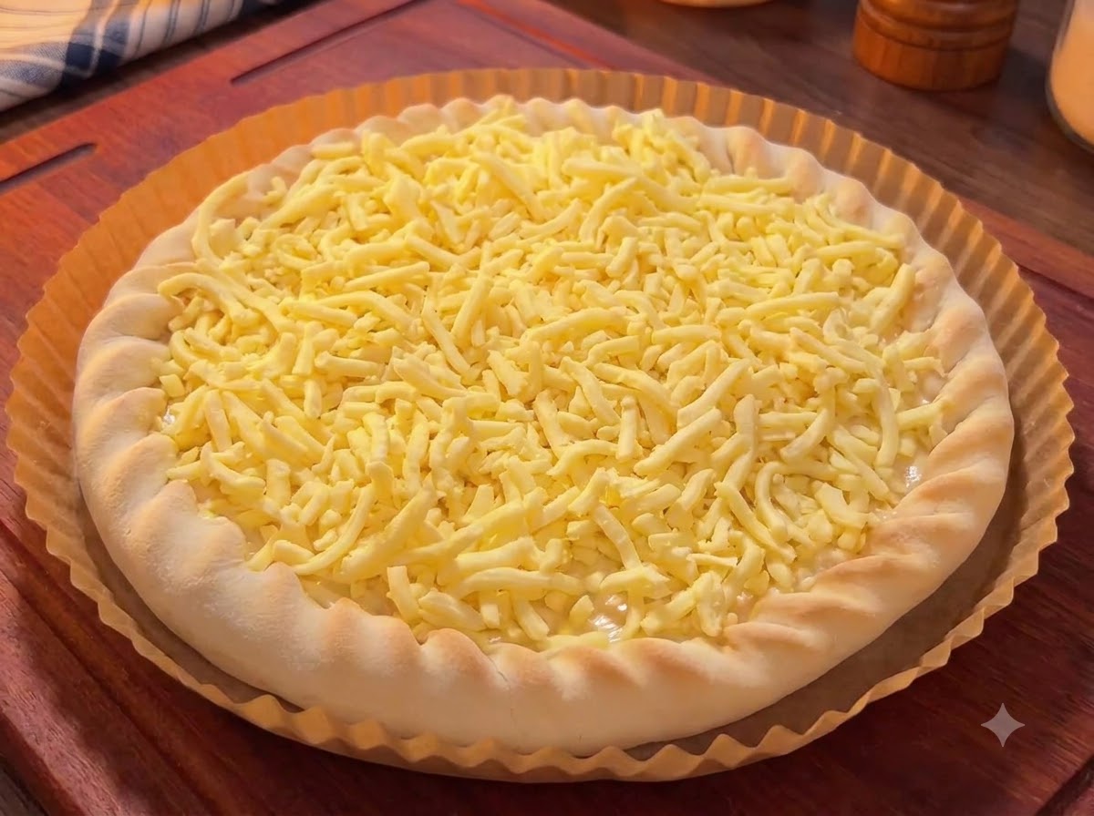 Una base de pizza cubierta con queso rallado, rematada con coloridos trozos de mango, fruta del dragón y cerezas.
