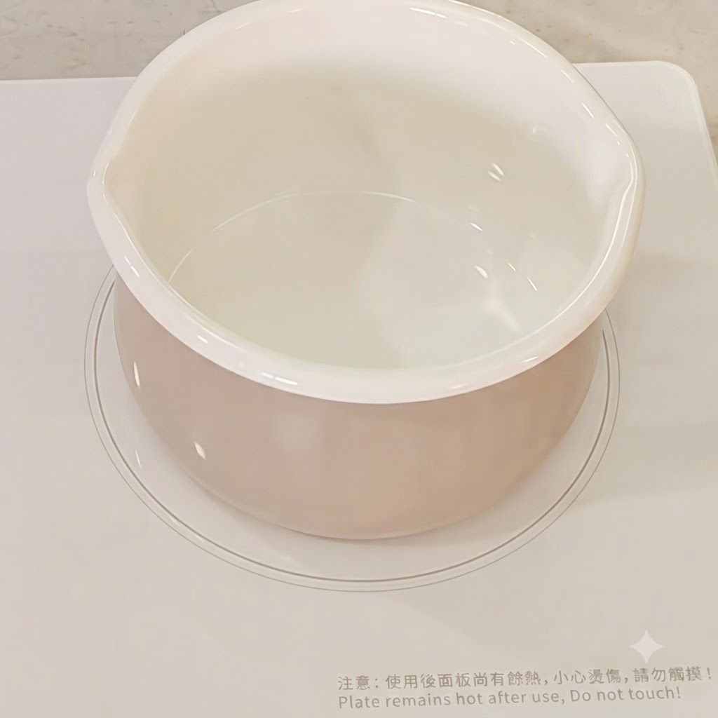 Agua vertida en una olla de cocción blanca en una estufa.