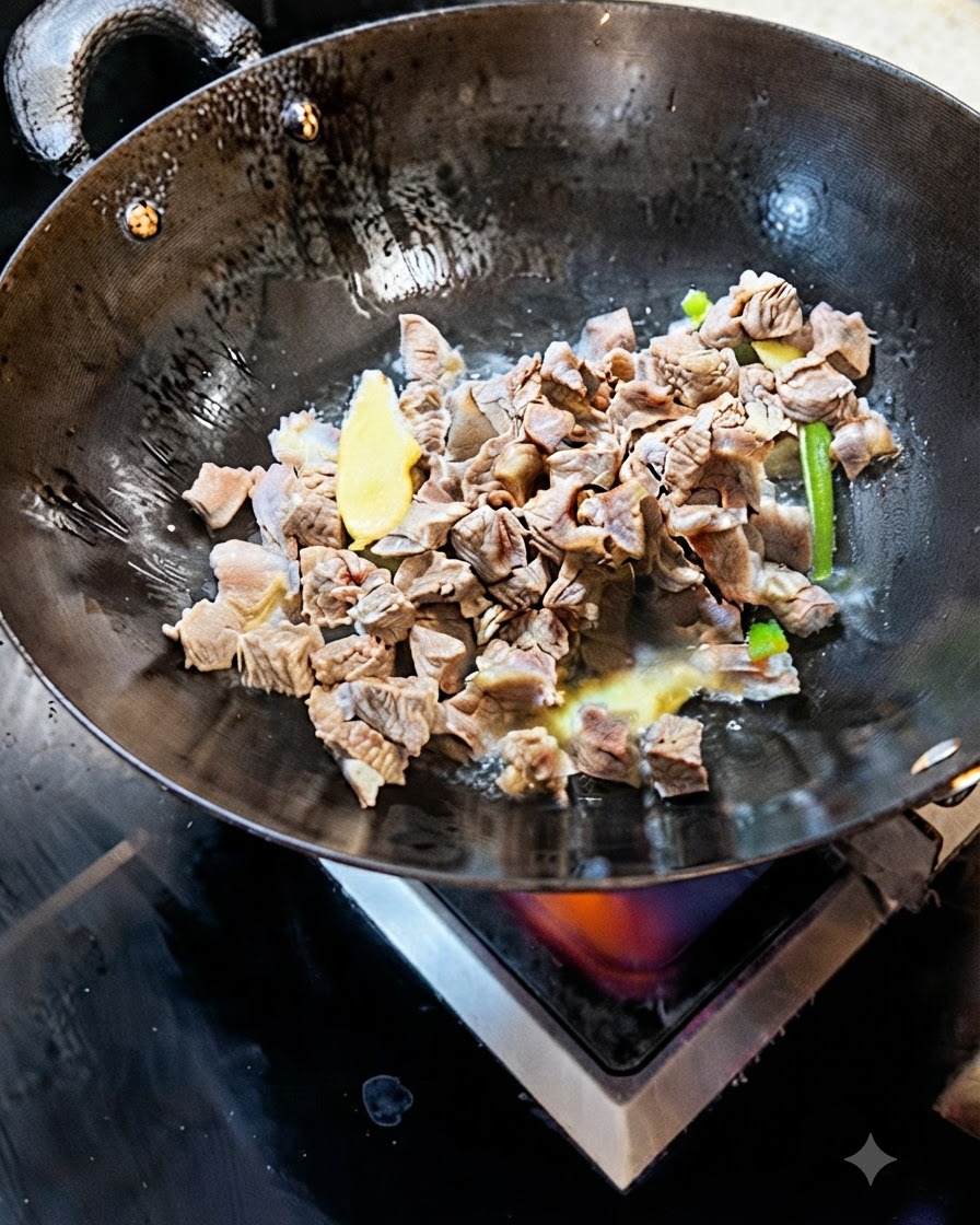 Cubos de carne blanqueada salteándose en un wok con rodajas de jengibre y cebolleta.
