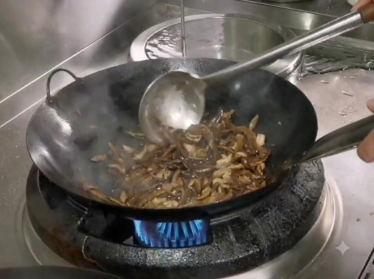 Sal y azúcar siendo revueltos en el wok con brotes de bambú y cerdo desmenuzado usando una espátula de metal.