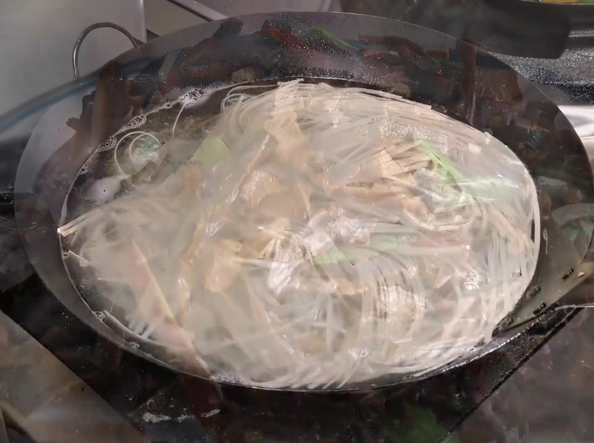 Fideos hirviendo vigorosamente en un wok grande lleno de agua.