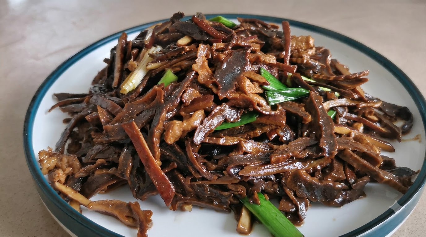Un plato de brotes de bambú seco y cerdo salteados con guarnición de brotes de ajo verde