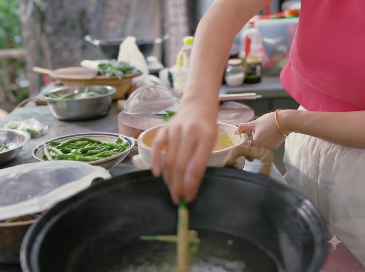 Una mano bajando judías verdes rebozadas en un wok con agua hirviendo.